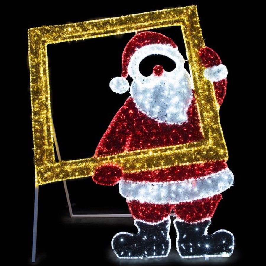 An illuminated Santa beside a gold picture frame for photographs.