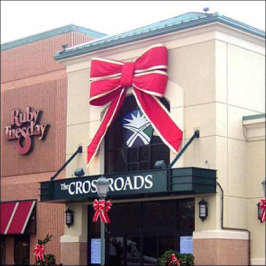A large red steel framed bow mounted on a commercial building exterior.