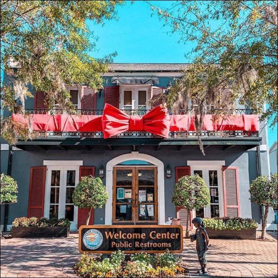 Red bows and garland along the facade and roofline of a commercial building.
