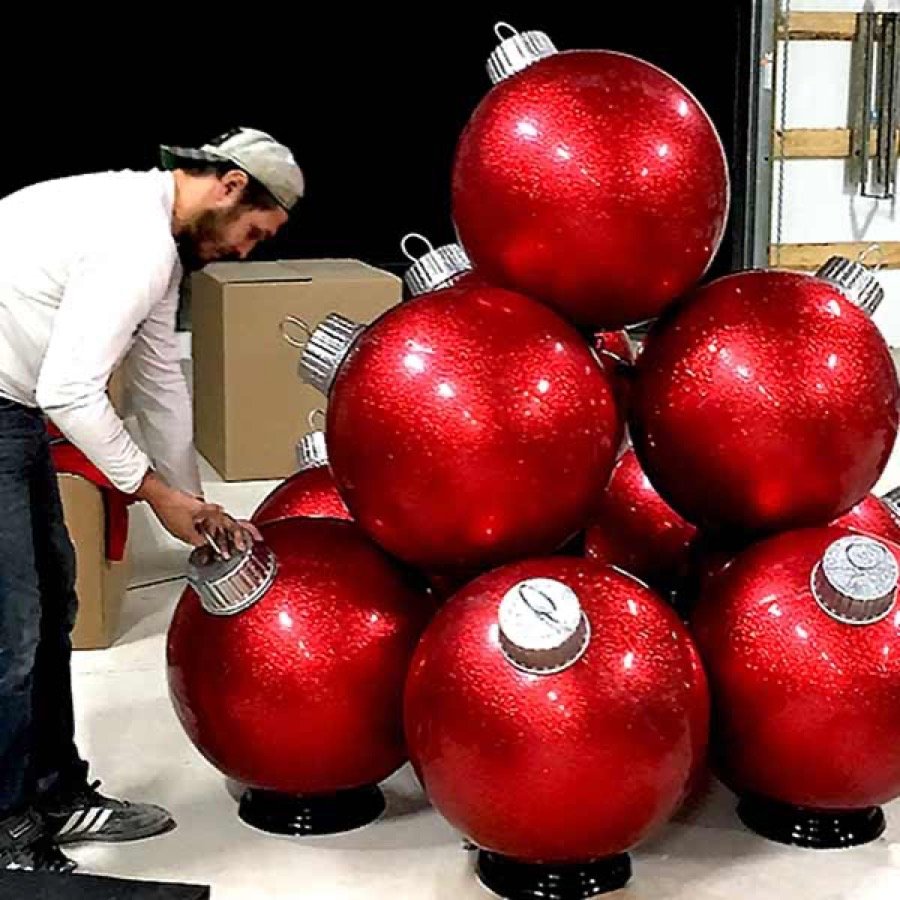 A crew member positioning a stack of oversized red ornament balls.