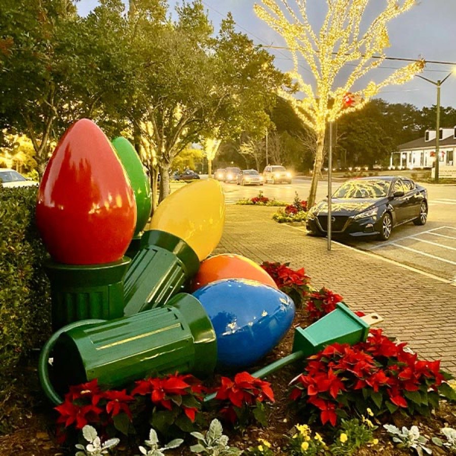 Oversized painted light bulb decorations grouped in a landscape bed.