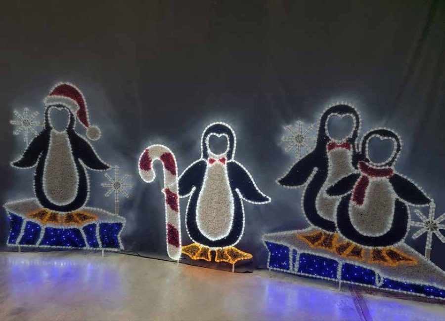 Four illuminated penguin figures beside oversized candy canes.