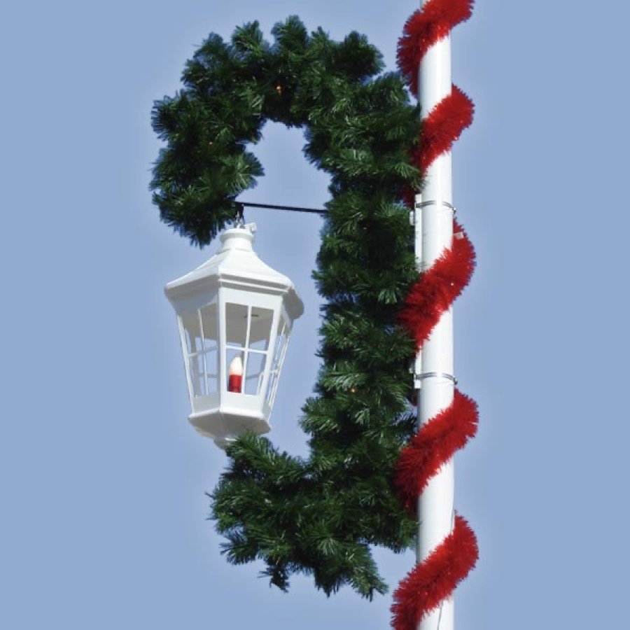 A garland wreath and candy cane scroll mounted on a street pole.