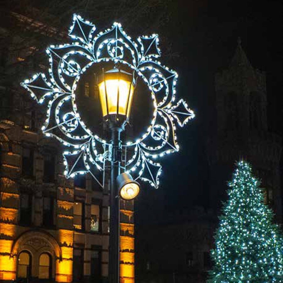 A lit halo frame wreath mounted around a street lamp at night.
