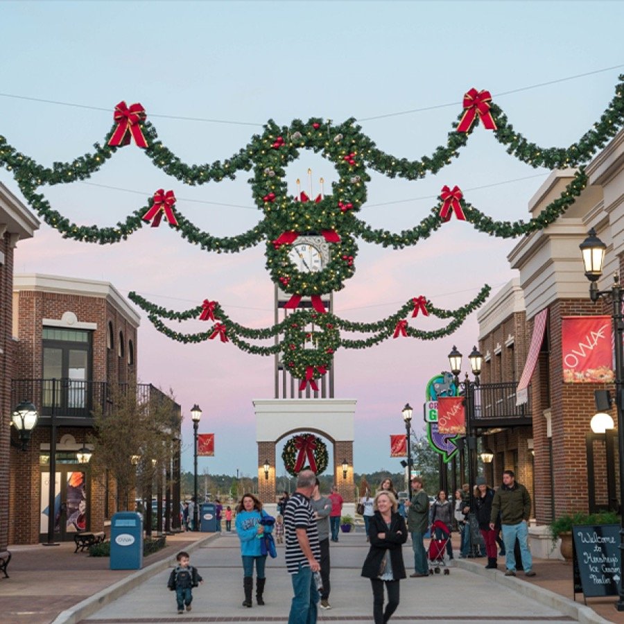 Overhead wreaths and garland strung above a pedestrian shopping street.