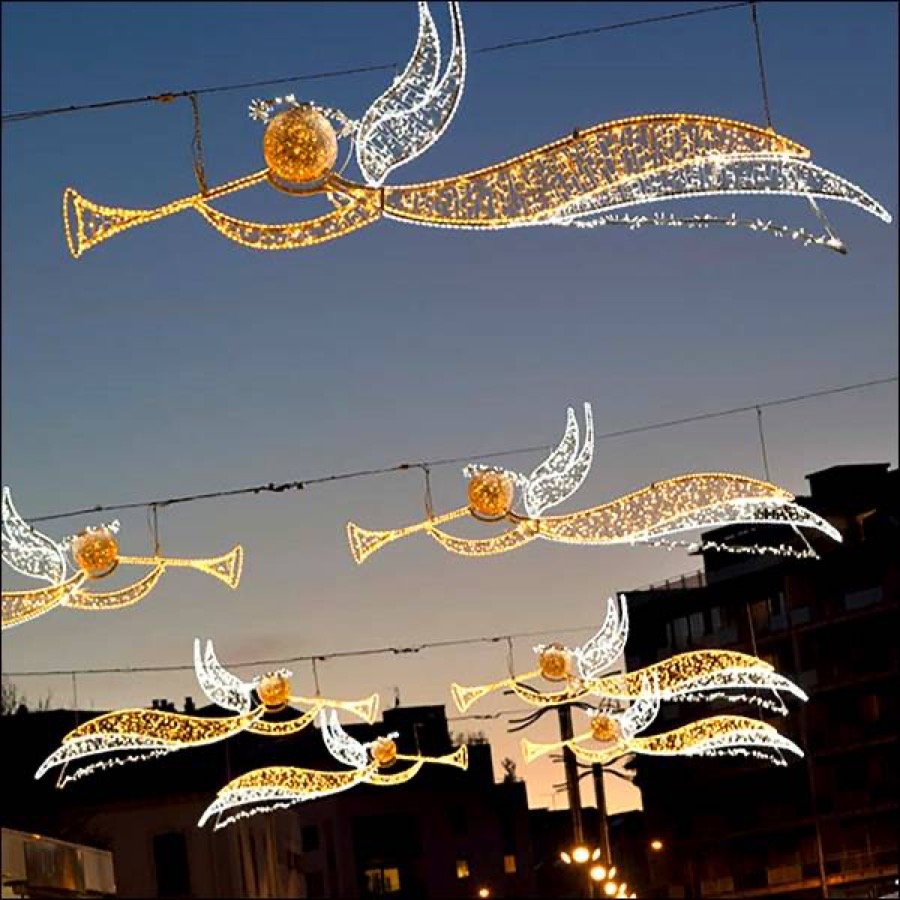 Lit angel ornaments suspended overhead above a street.