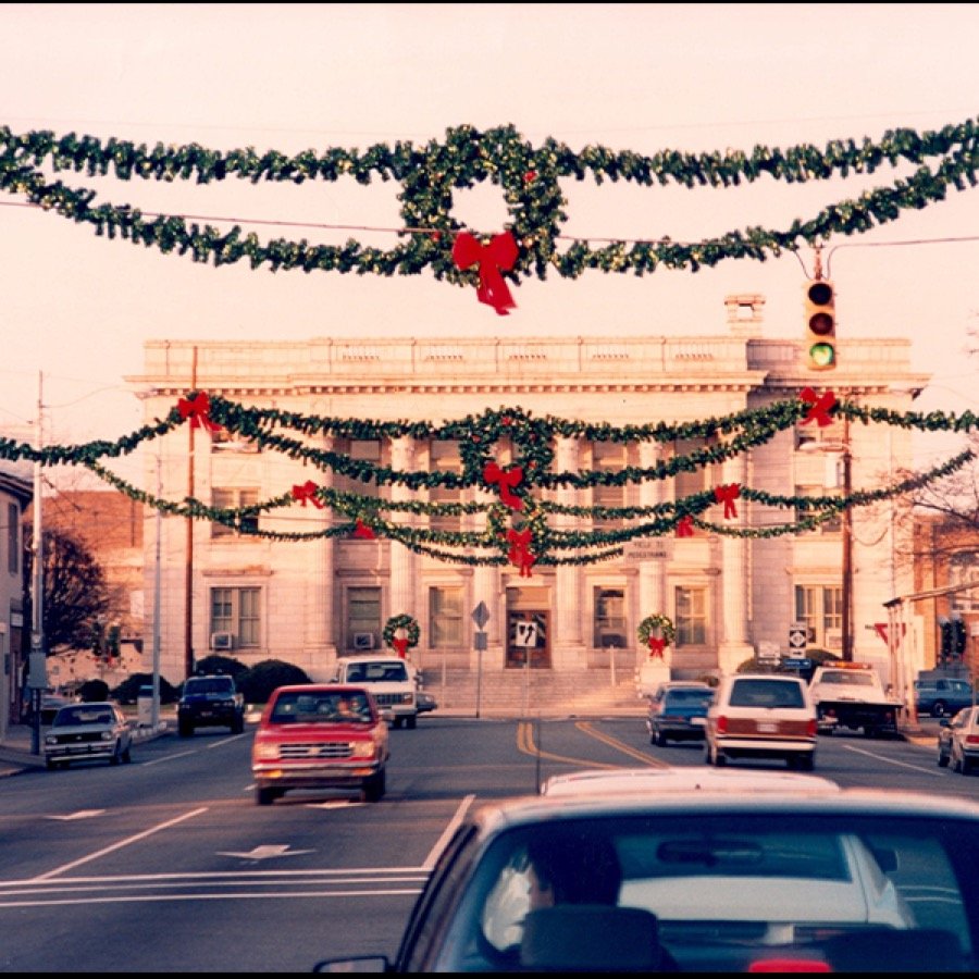 Traditional wreaths and garland suspended across a street above traffic.