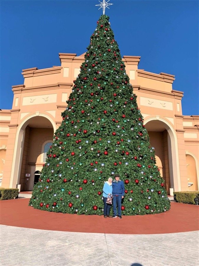 People standing beside a large commercial display tree in a public square.