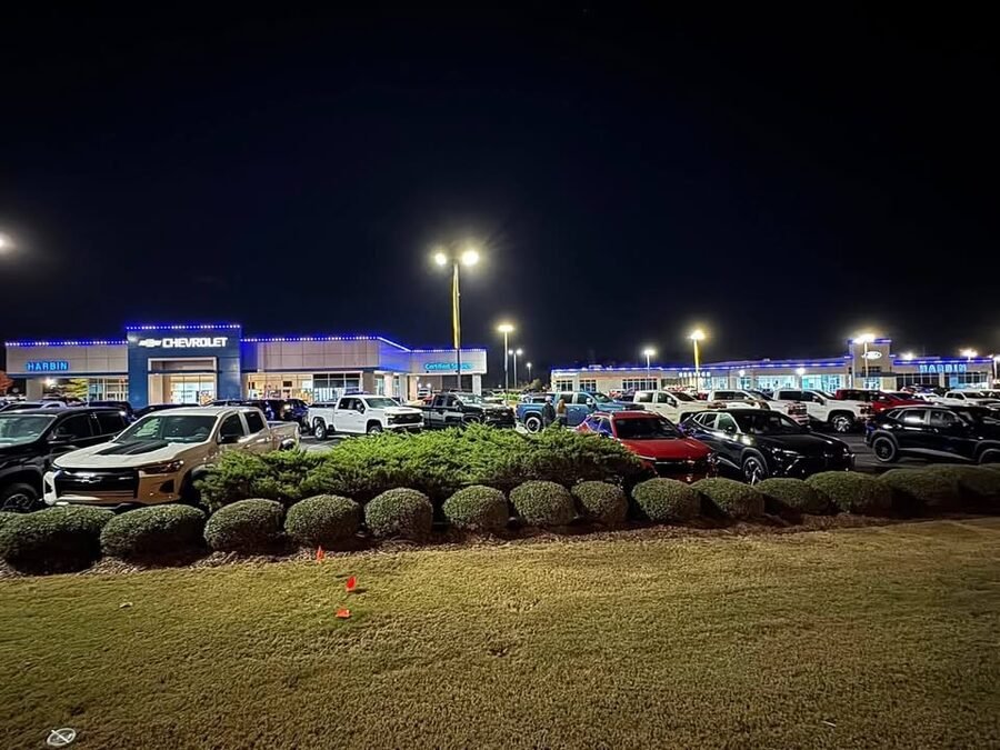 A Chevrolet dealership at night with blue permanent lighting along the roofline above the showroom and lot.