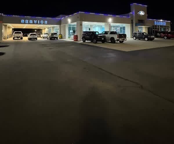 A Ford dealership at night with blue permanent lighting along the service canopy and showroom roofline.
